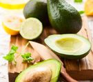 Holzbrett mit Avocados, eine aufgeschnitten, Zitrone und Messer