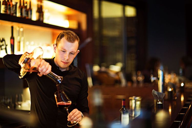 Mann beim Dekantieren von Rotwein