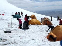 Leute und Zelte auf einem schneebedeckten Hang im Gebirge
