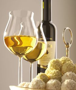Weißwein in einer Flasche und zwei Weingläsern sowie runde, weiße Pralinen