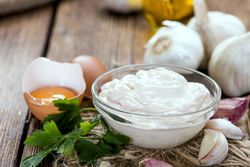 Weiße Creme aus Aioli, Knoblauch und Öl, aufgeschlagenes Ei und Knoblauchzehen