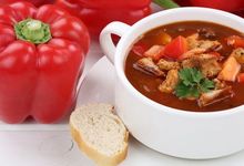 Rote Paprika, Baguette und Schüssel mit Suppe aus unter anderem Tomaten und Rindergulasch