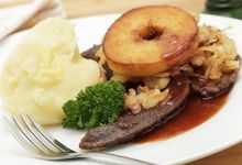 Teller mit Gabel und Kalbsleber sowie Kartoffelbrei, Apfelring und Petersilie