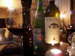 Glas und Flasche mit Rotwein, Mineralwasser und Pfeffermühle