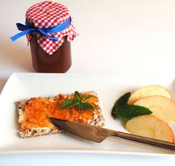 Marmeladenglas, Teller mit Apfelschnitten, Knäckebrot mit Apfel-Minze-Gelee und Messer