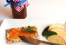 Marmeladenglas, Teller mit Apfelschnitten, Knäckebrot mit Apfel-Minze-Gelee und Messer