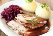 Teller mit Schmorbraten, zwei Knödeln und Rotkraut