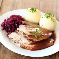 Teller mit Schmorbraten, zwei Knödeln und Rotkraut