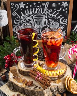 Zwei mit Glühwein gefüllte Gläser auf Holzscheiben mit Zimt, Zitronen etc.