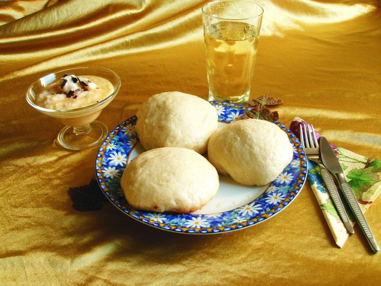Drei Dampfnudeln auf einem Teller, Besteck, Weinsauce und Glas mit Wein