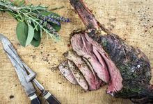 Gebratene Hirschkeule auf einem Holzbrett mit Messer und Fleischgabel