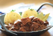 Metallteller mit Schweinepfeffer und Klößen