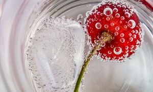 Eine rote Kirsche in perlendem Schnaps