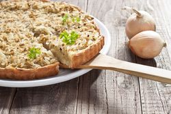 Teller mit Zwiebelkuchen, daneben zwei Zwiebeln