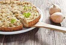 Teller mit Zwiebelkuchen, daneben zwei Zwiebeln