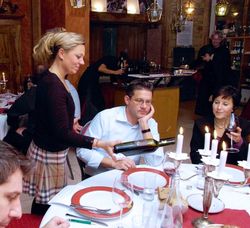 Natalie Lumpp beim Kredenzen von Wein am gedeckten Tisch mit Gästen