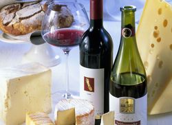 Verschiedene Käsesorten mit Rotwein in zwei Flaschen und einem Glas sowie Brot