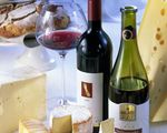 Verschiedene Käsesorten mit Rotwein in zwei Flaschen und einem Glas sowie Brot