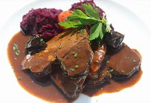 Teller mit Wildschwein-Sauerbraten, Sauce und Rotkraut