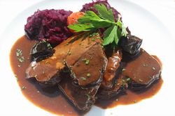 Teller mit Wildschwein-Sauerbraten, Sauce und Rotkraut