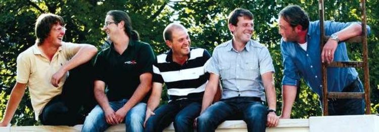 Fünf Männer auf einer Mauer sitzend