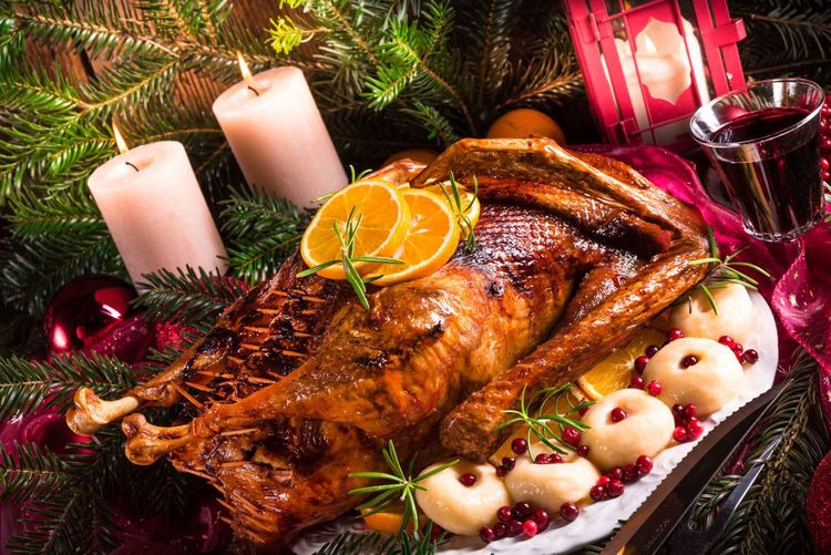 Gebratene Gans mit Weihnachtsdeko, zwei brennende Kerzen und Glühwein
