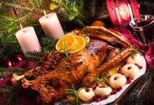 Gebratene Gans mit Weihnachtsdeko, zwei brennende Kerzen und Glühwein