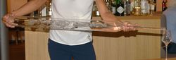 Mann schenkt aus Riesenflasche mit Schnaps in ein Glas ein.