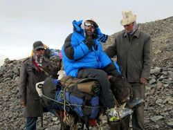 Gruppenfoto mit drei dick angezogenen Männern im Gebirge, einer auf einem Esel sitzend