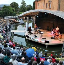 Julia Neigel mit Band auf einer Bühne in einem Teich und Zuschauer auf Sitzplätzen